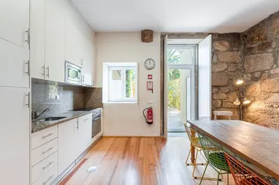 a kitchen with white cabinets and a stone wall at GuestReady - Breyner Stonewall Haven in Porto