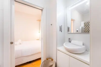 a white bathroom with a sink and a mirror at GuestReady - Breyner Stonewall Haven in Porto