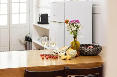 a table with two wine glasses and a vase with flowers at Porto 61 - Bright 2BR w/ Balcony by LovelyStay in Porto