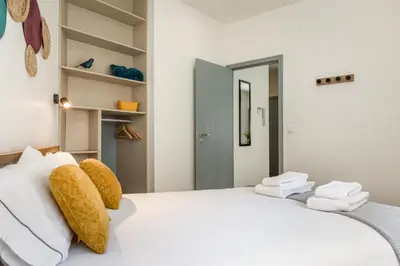 a white bedroom with a large white bed with yellow pillows at Alma Bonfim Apartments in Porto