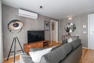 a living room with a couch and a flat screen tv at João das Regras 321 by LovelyStay in Porto