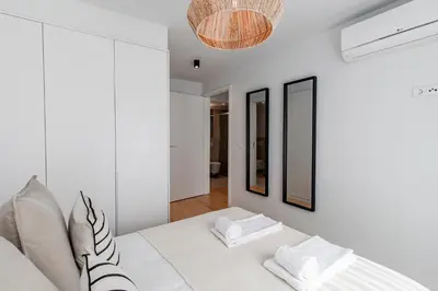 a white bedroom with a white bed and a mirror at João das Regras 321 by LovelyStay in Porto