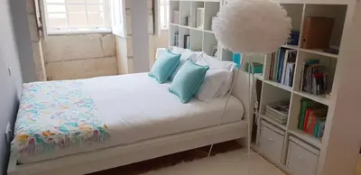 a bedroom with a bed with blue pillows and a book shelf at Toctoc Studio in Porto