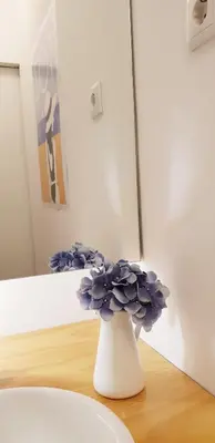 a white vase with blue flowers sitting on a table at Toctoc Studio in Porto