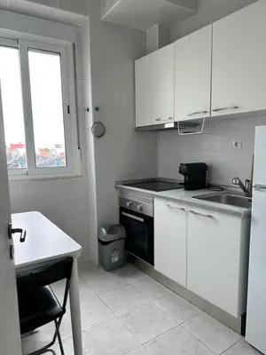 a kitchen with white cabinets and a sink and a window at Vicky Porto in Porto