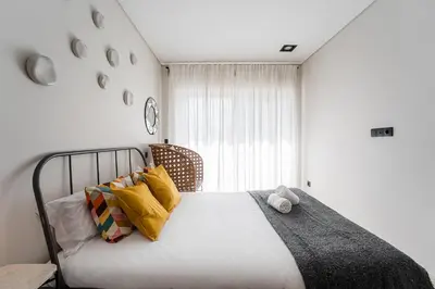 a bedroom with a bed with yellow pillows and a window at GuestReady - Quental Wallpaper near Marquês Square in Porto