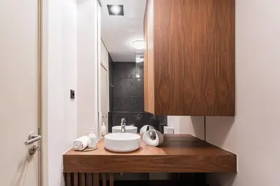 a bathroom with a sink and a wooden cabinet at GuestReady - Quental Wallpaper near Marquês Square in Porto
