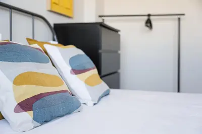 a bedroom with a bed with colorful pillows at GuestReady - Quental Wallpaper near Marquês Square in Porto