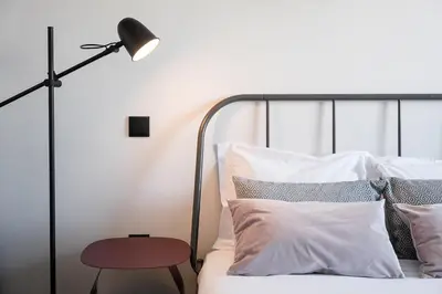 a bedroom with a bed with a lamp and pillows at GuestReady - Quental Wallpaper near Marquês Square in Porto