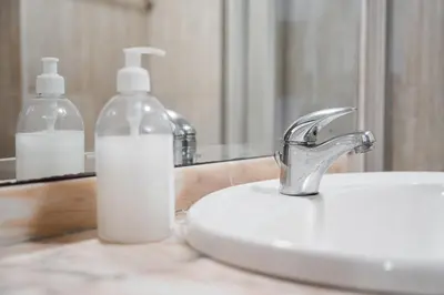 a bathroom sink with a bottle of soap next to a mirror at GuestReady - Portrait with a view in Porto