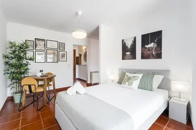 a white bedroom with a bed and a table at GuestReady - Portrait with a view in Porto