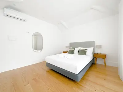 a white bedroom with a bed and a wooden floor at Vibrant Host -Bonfim in Porto