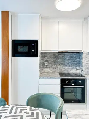 a kitchen with white cabinets and a table and chairs at HM - Ribeira Historical Apartment in Porto