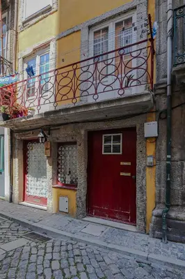 a building with a red door and a balcony at HM - Ribeira Historical Apartment in Porto
