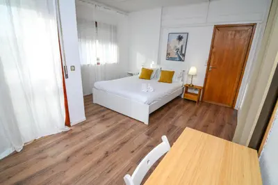a bedroom with a white bed and a table at Travel & Live Fernão Magalhães in Porto