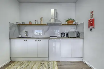 a small kitchen with white cabinets and a microwave at Travel & Live Fernão Magalhães in Porto