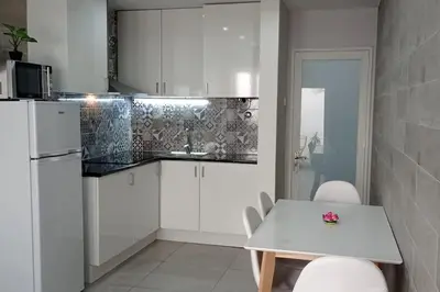 a kitchen with white cabinets and a white table and chairs at Torre dos Clérigos Apartment in Porto