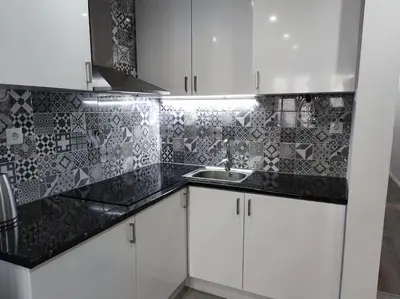 a kitchen with white cabinets and a black counter top at Torre dos Clérigos Apartment in Porto