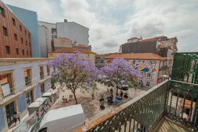 a city street with purple trees and buildings at Moinho de Vento Studios in Porto