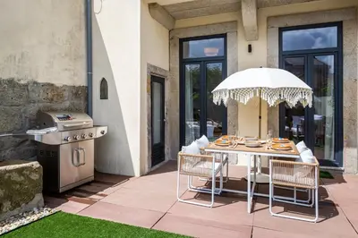 a patio with a table with an umbrella and a grill at OPO Vale Formoso II Garden & BBQ in Porto