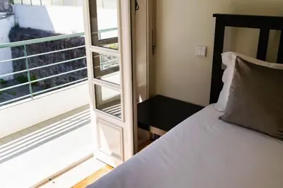 a bedroom with a bed next to a window at Charmant appartement climatisé avec balcons in Porto
