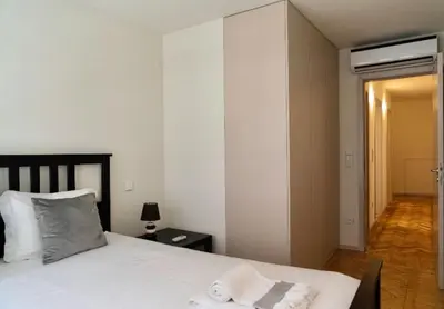 a bedroom with a white bed with a towel on it at Charmant appartement climatisé avec balcons in Porto