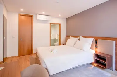 a bedroom with a large white bed and a chair at Alliança Suites 1909 - Porto in Porto