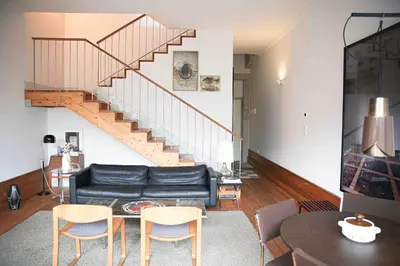 a living room with a black couch and a staircase at Design Poveiros Duplex in Porto