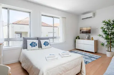 a white bedroom with a large bed and windows at Host Wise - Comfy Sunny Flat - Prime Location in Porto