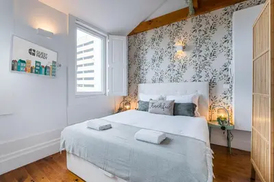 a bedroom with a white bed with a floral wallpaper at GuestReady - Beer Garden in Porto