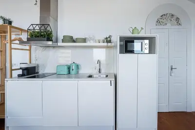 a white kitchen with a refrigerator and a microwave at GuestReady - Beer Garden in Porto