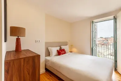 a white bedroom with a bed and a window at Dasi House in Porto