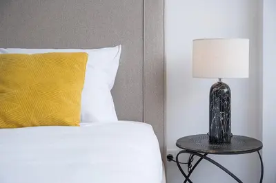 a bed with a yellow pillow and a table with a lamp at GuestReady - Sedona lodge near Palácio de Cristal in Porto