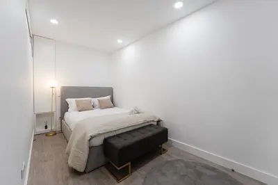 a white bedroom with a bed and a black ottoman at GuestReady - Sedona lodge near Palácio de Cristal in Porto