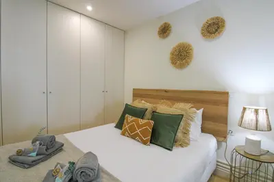 a bedroom with a large white bed with green pillows at La Vida in Porto Unique in Porto