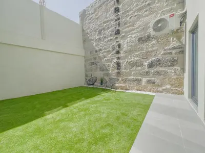 a room with a stone wall and green grass at Vibrant Host-Campo 24 Agosto in Porto
