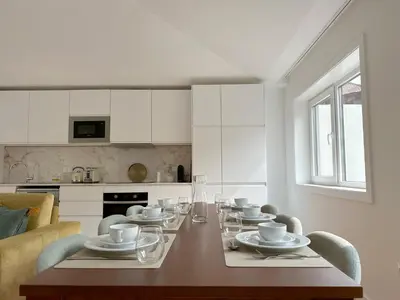 a dining room table with chairs and a kitchen at Vibrant Host-Campo 24 Agosto in Porto