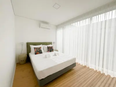 a white bedroom with a large bed and a window at Vibrant Host-Campo 24 Agosto in Porto