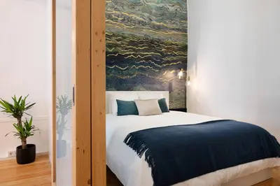 a bedroom with a large bed with a painting on the wall at Sao Domingos Stylish Apartment in Porto