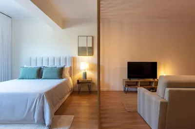 a bedroom with a white bed and a television at DOISPONTOZERO Bragas in Porto