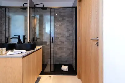 a bathroom with a sink and a glass shower at DOISPONTOZERO Bragas in Porto
