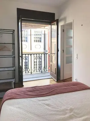 a bedroom with a bed and a window with a balcony at The Flat in Porto