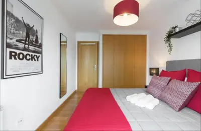 a bedroom with a bed with red pillows and a red rug at Host Wise - Deluxe Modern Flat w Balcony in Porto