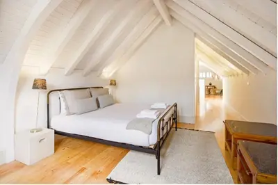 a bedroom with a bed with white sheets and a table at Mouzinho 202 in Porto