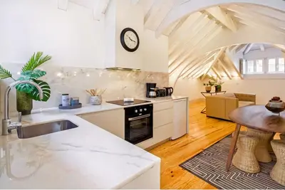 a kitchen with white counters and a table in a room at Mouzinho 202 in Porto