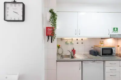 a kitchen with white cabinets and a clock on the wall at Host Wise - Cool Flat - City Center near Aliados in Porto