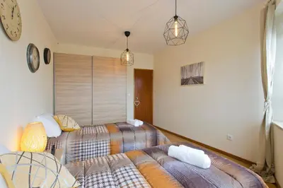 a bedroom with two beds and a clock on the wall at Host Wise - Spacious Trendy Flat w Netflix - Central Location in Porto