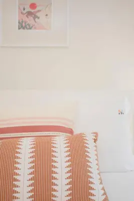 a bed with an orange and white pillow on it at Liiiving in Porto - Haven Pool Apartment in Porto