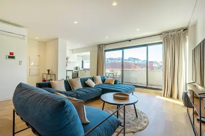 a living room with a blue couch and a large window at Large Terrace in Paraiso III in Porto