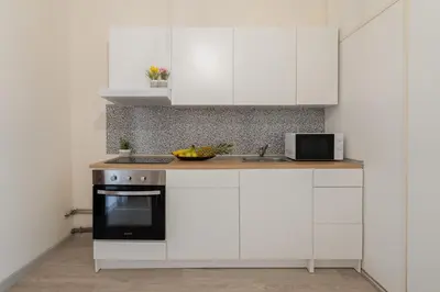 a kitchen with white cabinets and a black oven at Host Wise - Cozy Sunny Flats - Ace Location in Porto